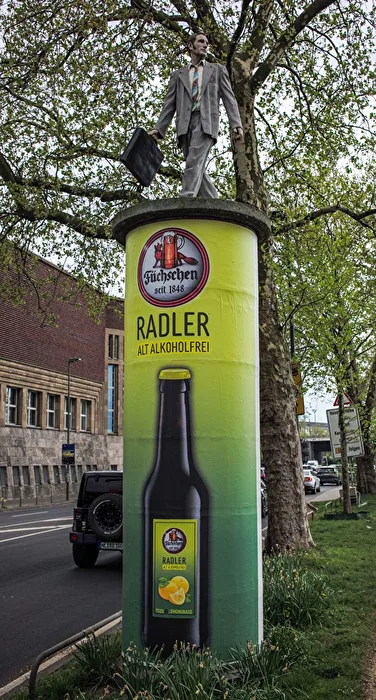 ...der Geschäftsmann auf dem Radlersockel